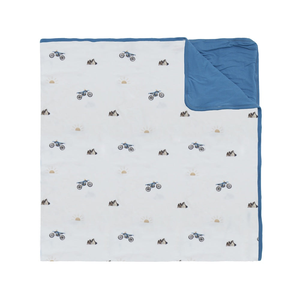 quilted child blanket in white dirtbike print, with marine blue color inside